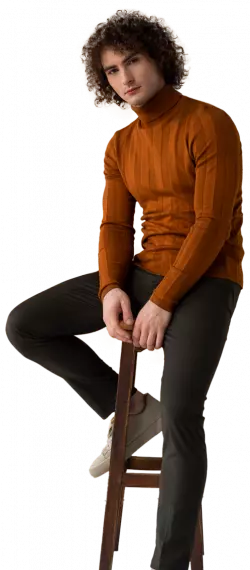 men fashion model with curly hair sitting in chair posing for a photo